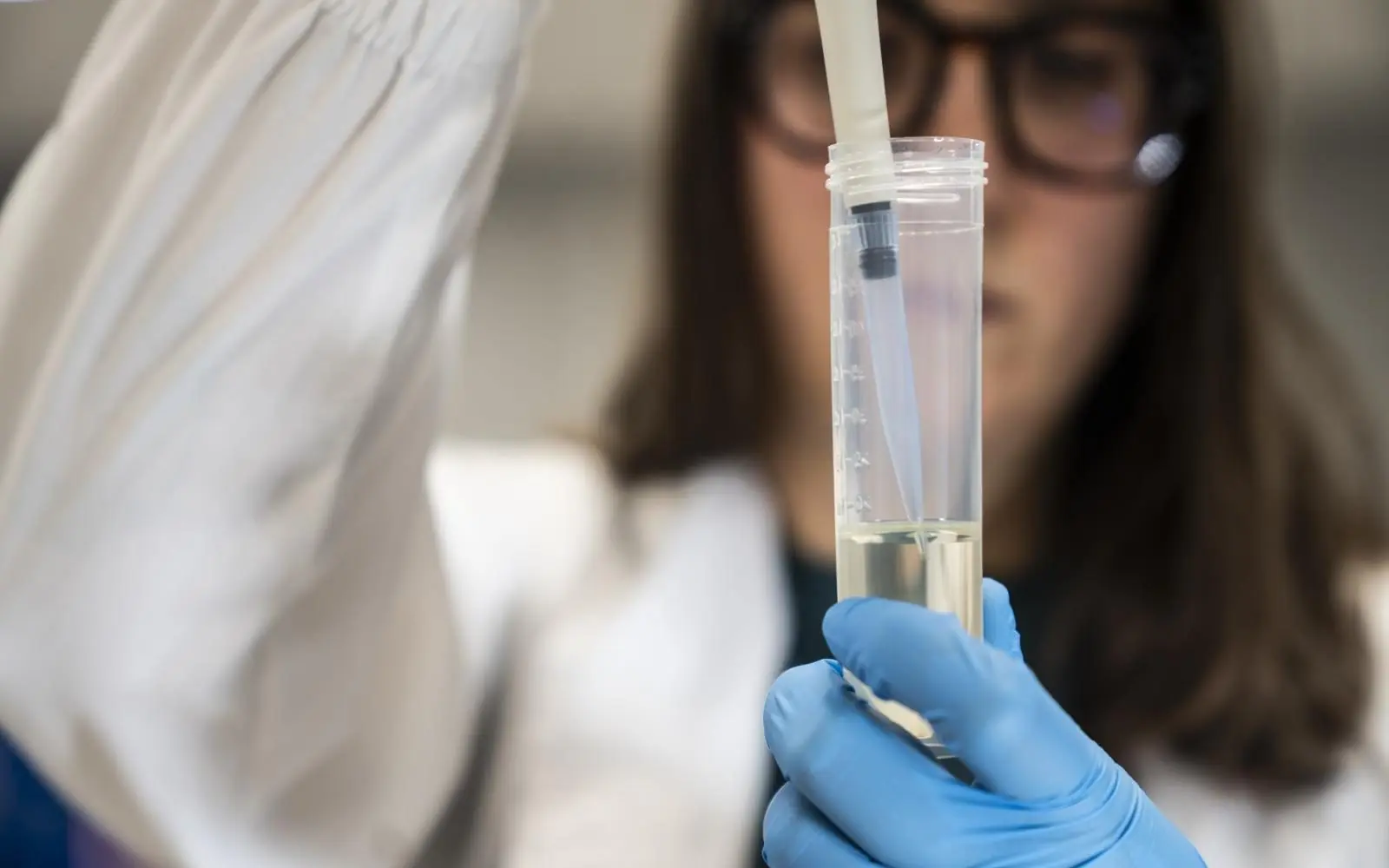 Laboratorio con mano che tiene un tubo da prova, attrezzatura da laboratorio. Gatti Filtrazioni Lubrificanti.