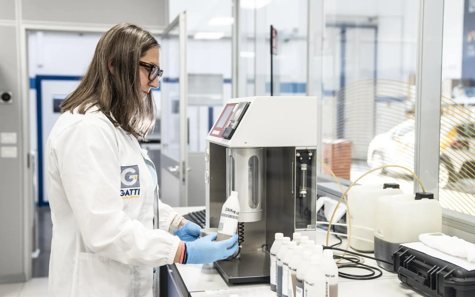 Laboratorio con scienziato in camice bianco, strumenti scientifici e uniforme. Gatti Filtrazioni Lubrificanti.